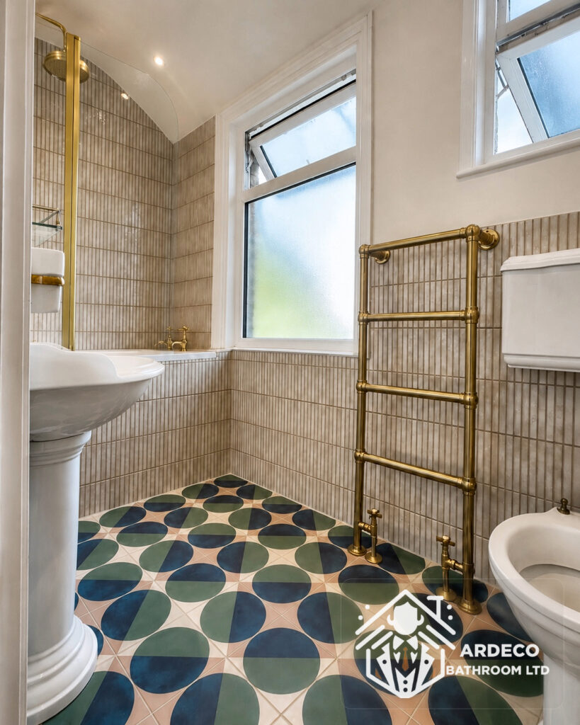 After renovation – bespoke floor tiling and brass towel radiator Patterned bathroom floor tiles, new tiled walls and a brass heated towel rail after renovation