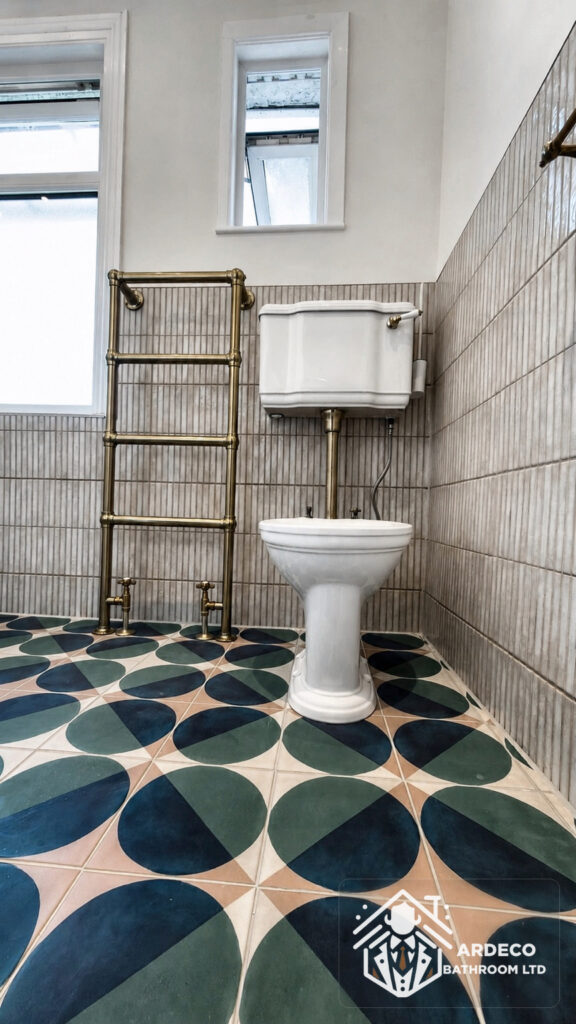 After renovation – toilet in combined bathroom Finished toilet area in a combined bathroom with patterned floor tiles and brass towel radiator